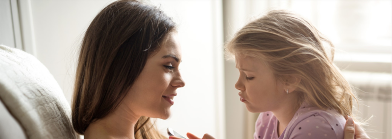 A mother and daughter sitting on a couch looking at each other.