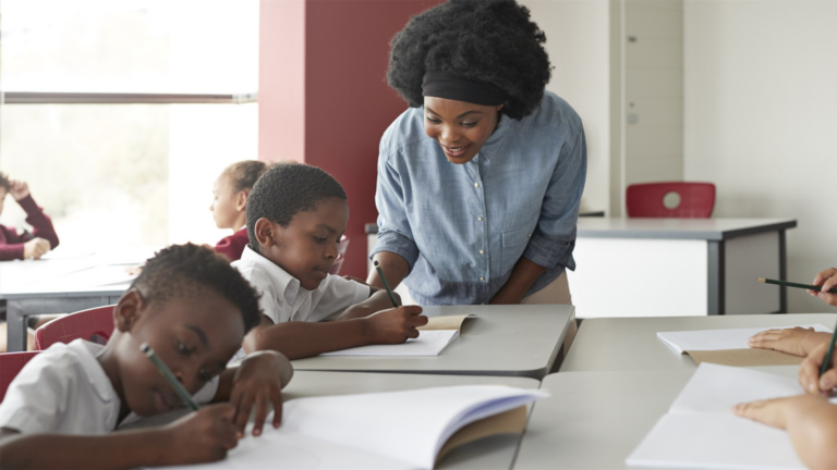 A teacher is helping a group of children in a classroom.