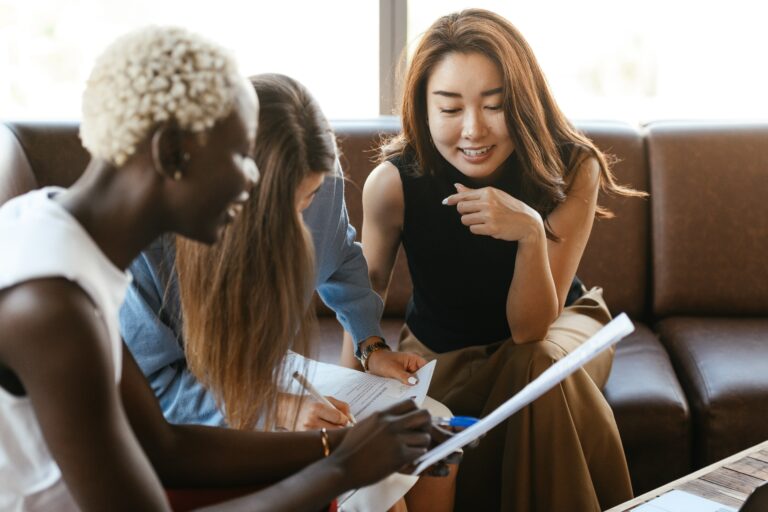 A group of women sitting around a couch and talking to each other under the guidance of a case manager.