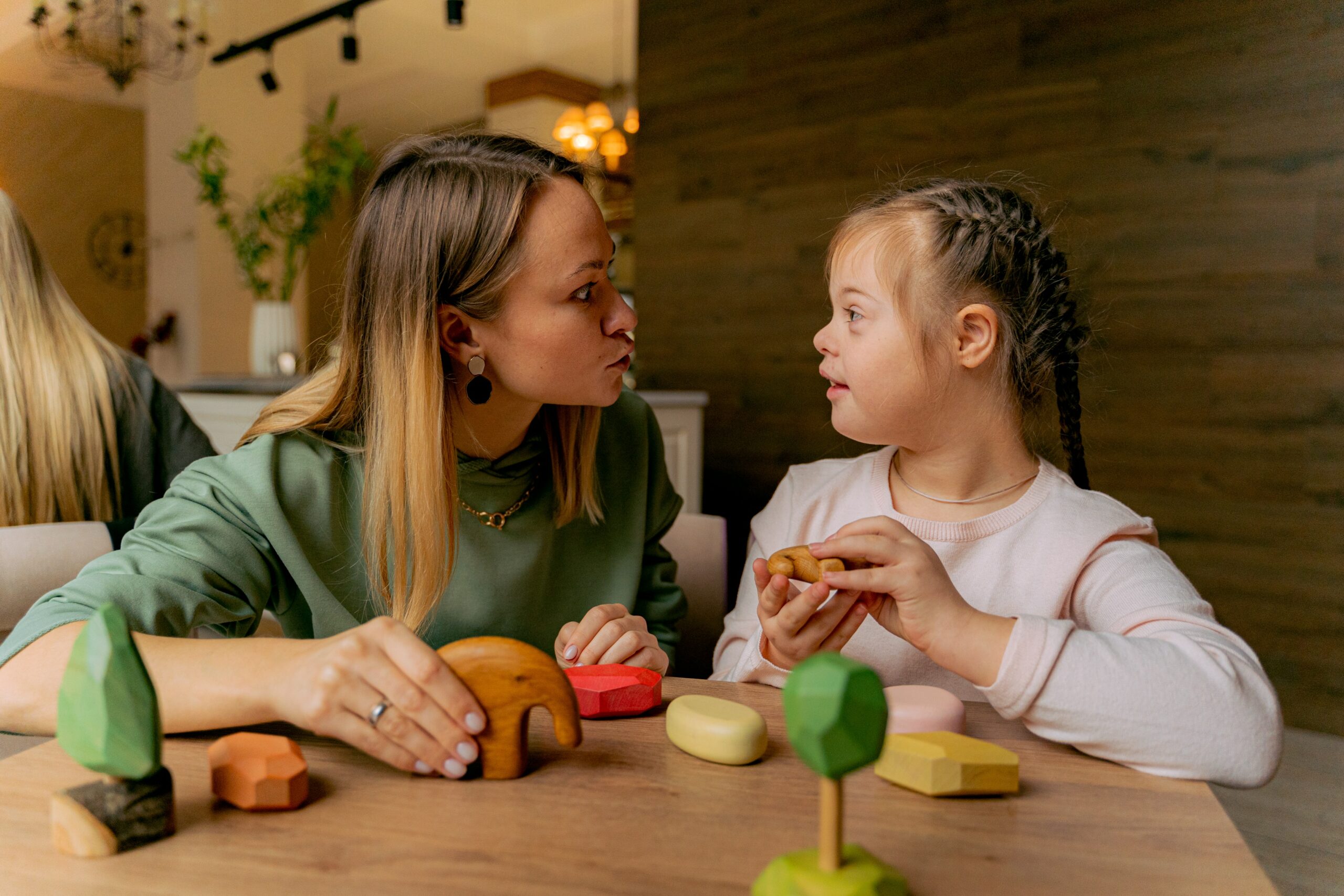 A mother and daughter exemplifying family values while playing with wooden toys in a restaurant.