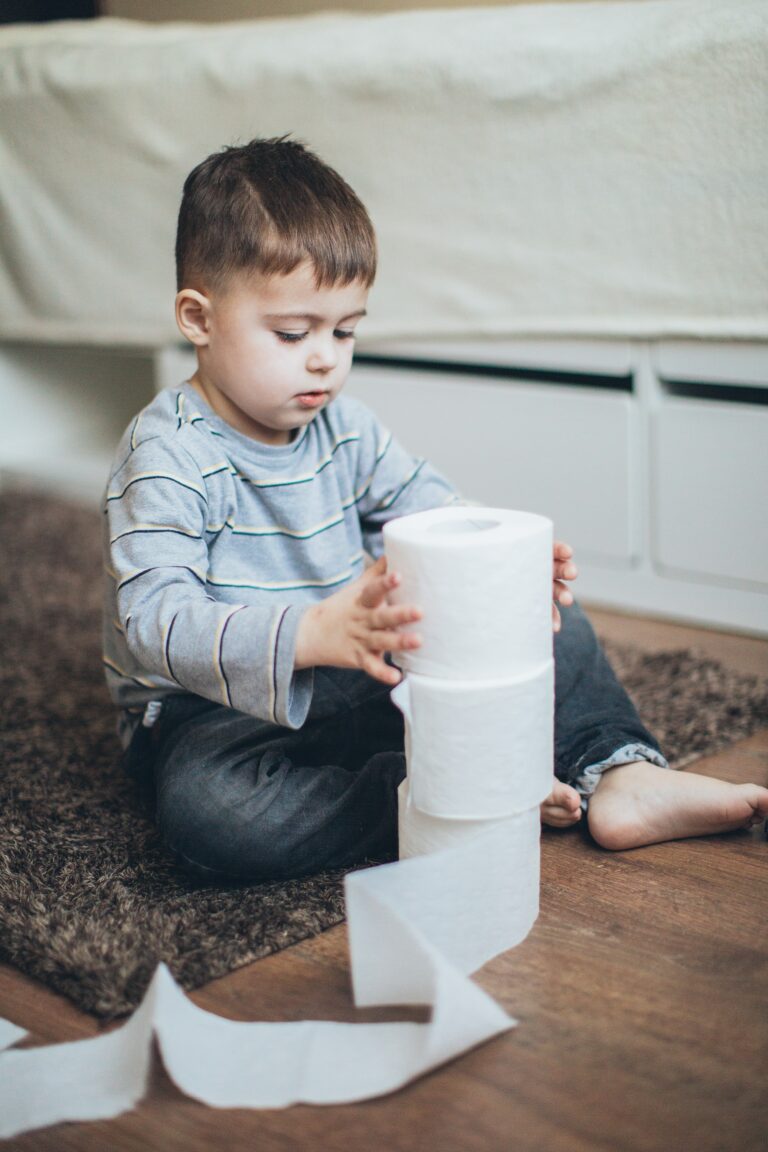 A young boy playing with a roll of toilet paper for fun.