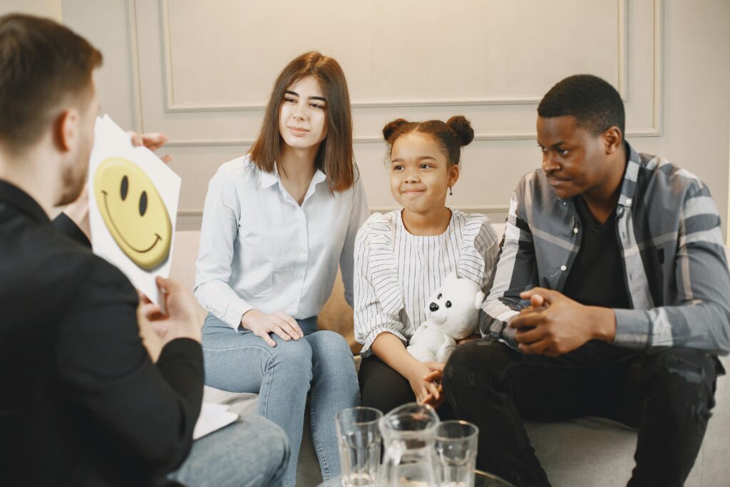 A group of children undergoing cognitive behaviour therapy on a couch with a smiley face.