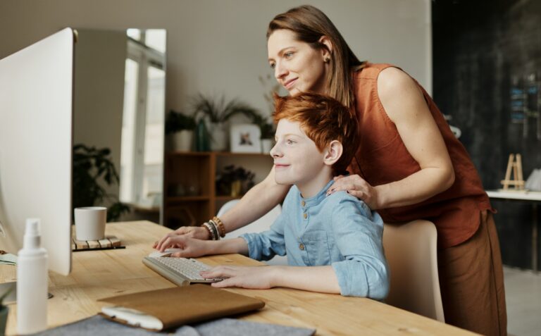 A woman and a boy using the Proloquo AAC program on a computer.