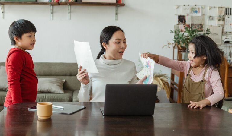 A woman and her children are using a laptop at home for the Picture Exchange Communication System Program.