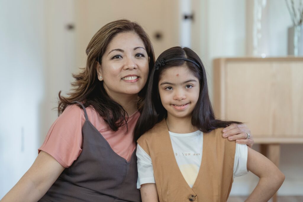 An asian woman posing for a photo with her daughter, who has Down syndrome.